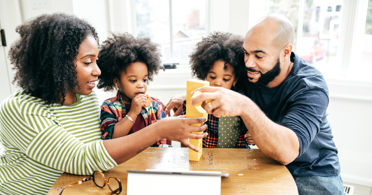 Mother and father with their twin girls playing with blocks